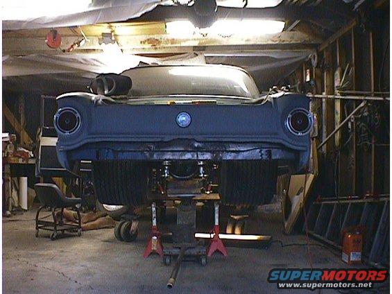 Rear view of a 1960 Ford Falcon being worked on in a garage, elevated on jack stands