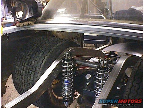 Custom rear suspension with dual shocks and a large tire in a vehicle's trunk area