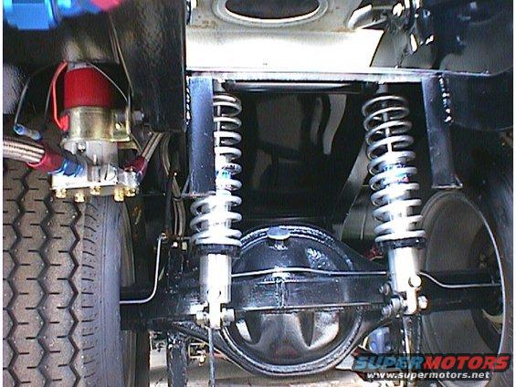 Close-up of a car's rear axle, differential, shocks, and suspension. A fuel pump is visible on the left