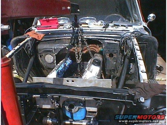 1960 Ford Falcon engine bay with engine being removed by hoist