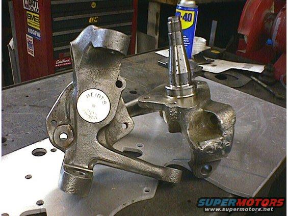 Two cast iron steering knuckles with a label reading HF 107 S on one
