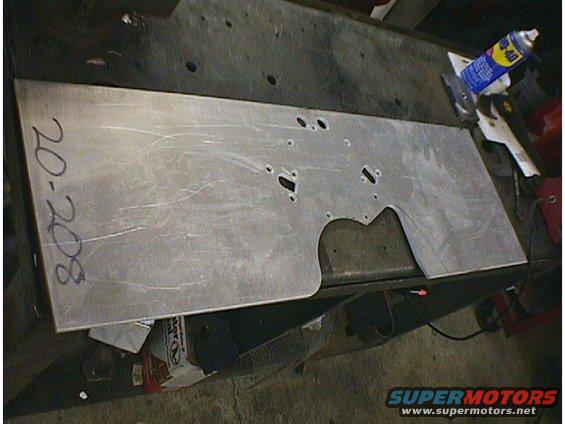 Metal plate with holes and '20-208' written on it, sitting on a workbench with a can of WD-40