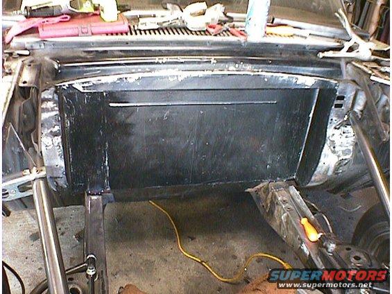 Car firewall area with black panel and yellow cord. Tools on top