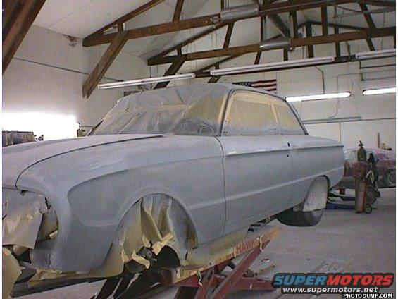 Car body shop, car on lift, covered in primer, windows taped off