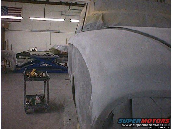Car bodywork covered in primer, side view. Workshop setting