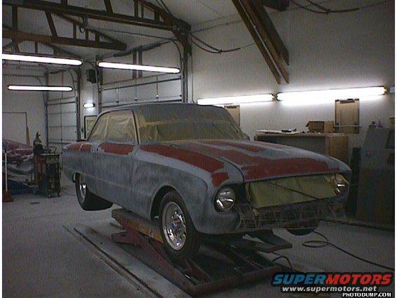 1960 Ford Falcon on a lift, covered in primer and masking tape in a garage