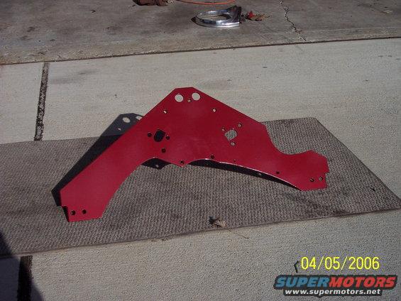 Red metal bracket on a mat, with a chrome trim piece in the background