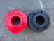2003 Ford Taurus - Two bushings, one red and one black, are shown side-by-side on a textured gray surface.