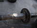 2003 Ford Taurus - Close-up of a vehicle strut assembly, showing the threaded rod and a rubber bushing.
