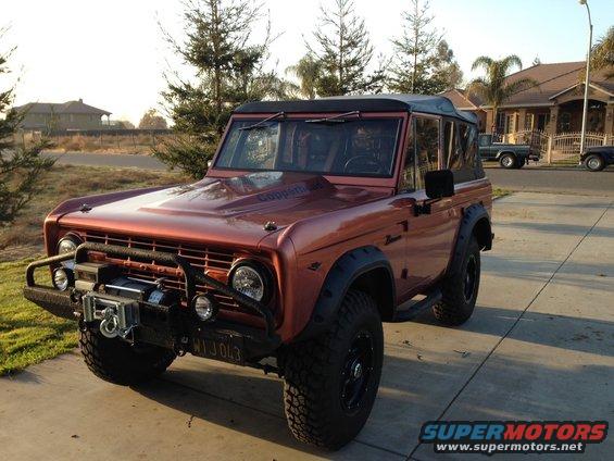 Orange 1968 Ford Bronco with black soft top, winch, and aftermarket bumper