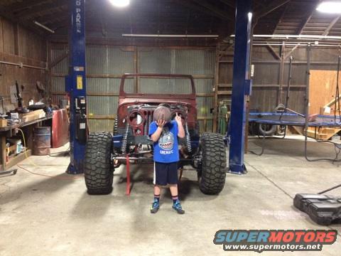 1985 Jeep CJ7 body on a lift, front view, with a child holding a basketball in front of it
