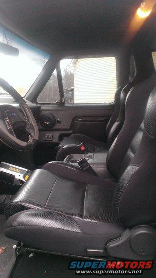 Interior view of a vehicle with black leather bucket seats and a steering wheel