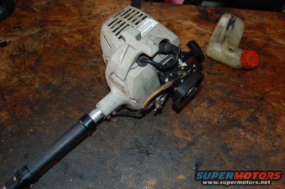 String trimmer engine and detached fuel tank on a workbench