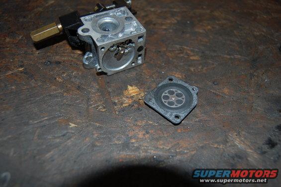 Carburetor body and diaphragm on a wooden workbench