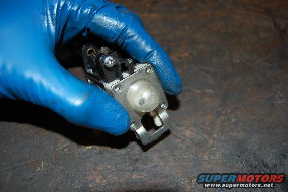 Carburetor with primer bulb held by gloved hand