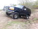 1995 Ford Bronco - 1995 Ford Bronco navigates a challenging off-road trail with its front wheels climbing an incline.