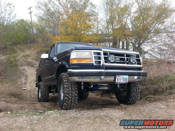 Blue 1995 Ford Bronco with off-road tires on a dirt path