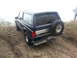 1995 Ford Bronco - Ford Bronco navigates an off-road trail, showing its rear profile and spare tire.