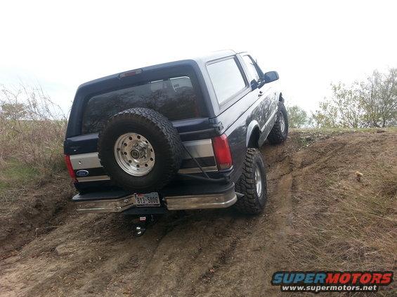 Ford Bronco climbing a dirt hill, spare tire mounted on the back