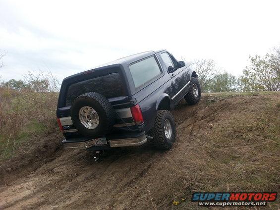 Dark blue SUV climbing a dirt hill, spare tire mounted on rear door, chrome bumper