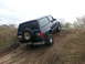 1995 Ford Bronco - Dark blue SUV navigates an off-road incline with a spare tire on the rear.