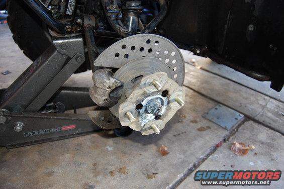 ATV wheel hub with brake rotor and caliper, supported by a jack
