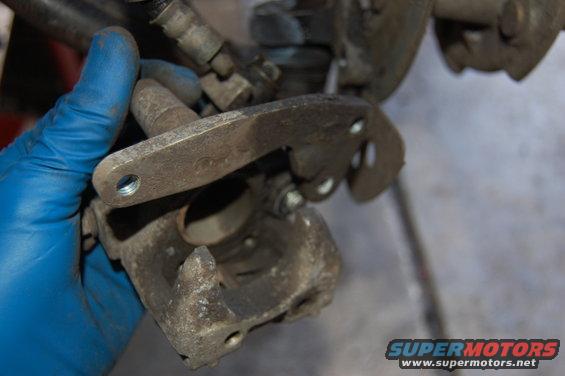 Brake caliper part held by gloved hand