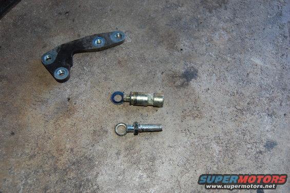 Metal bracket and two eye bolt-like parts on concrete