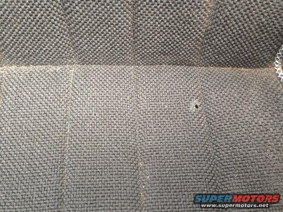 Close-up of gray woven seat fabric with a small hole