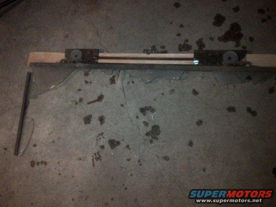 Wooden beam with metal rollers on a cracked concrete floor with oil stains