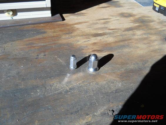 Two lug nuts on a wooden surface