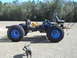 1992 Ford Bronco - A custom-built vehicle chassis with oversized tires and a blue engine sits outdoors with a dog in the foreground.