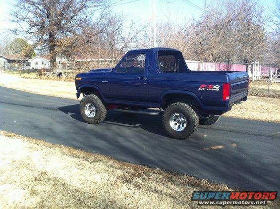 Blue Ford Bronco with FX4 Off Road decals, lifted suspension, and chrome wheels on a paved road