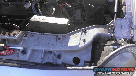 Engine bay with fuse box, wiring, and a screwdriver on a panel