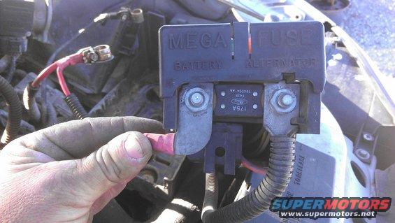 Engine bay fuse box with red battery cable being held, "MEGA FUSE" label visible