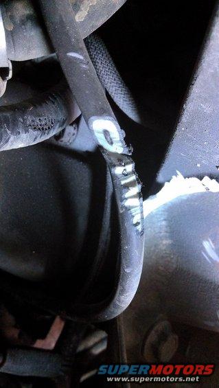 Close-up of a damaged rubber hose with white markings and a braided sleeve