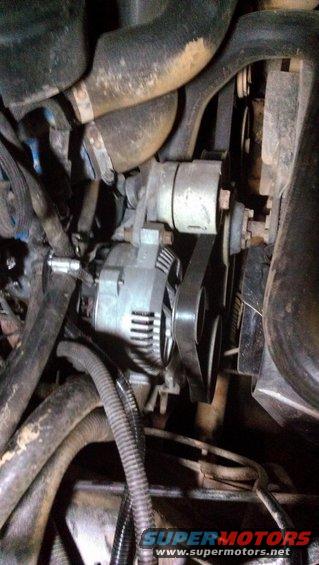 Engine alternator with belt and hoses. Text 'SUPERMOTORS WWW.SUPERMOTORS.NET' visible