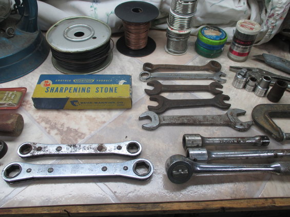 collection of wrenches, sockets, wire spools, and a sharpening stone