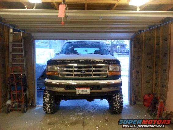 1996 Ford Bronco front view parked in a garage with snow on tires and hood