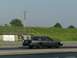2004 Ford Crown Victoria - A gray 2004 Ford Crown Victoria is seen on a drag strip with racing numbers on its window.