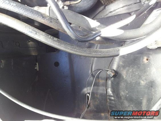 Engine bay with hoses and wiring, dark metal surfaces, some rust spots