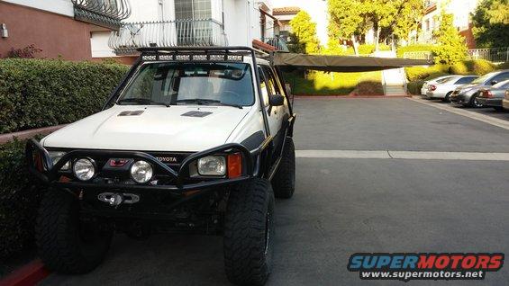White Toyota 4Runner with aftermarket bumper and awning, parked in a lot