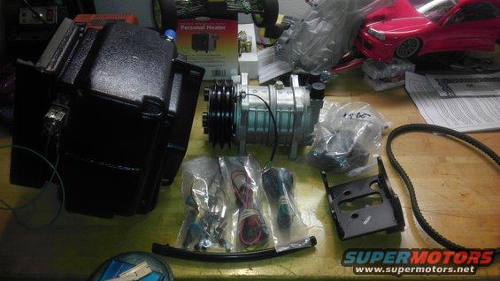 Air conditioning compressor, black housing, wiring, and belt laid out on a table