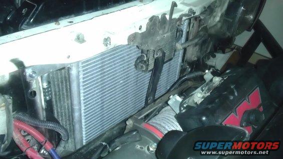 Aftermarket oil cooler mounted in front of radiator, with a winch visible below. Wiring and hoses are present
