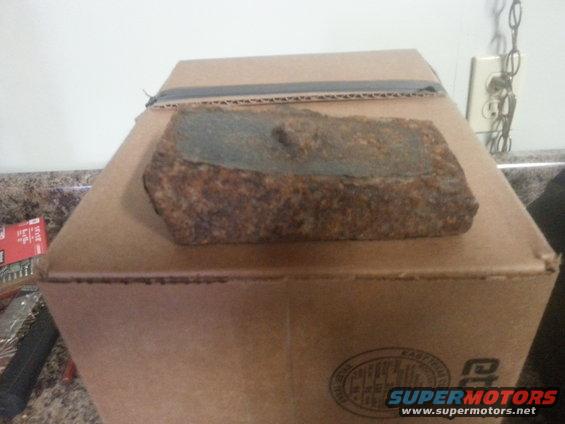 Rusty metal object on top of a cardboard box. Text on box reads SUPERMOTORS
