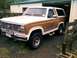 1982 Ford Bronco - This two-tone brown and white Ford Bronco is parked in front of a garage, showing its front three-quarter view.