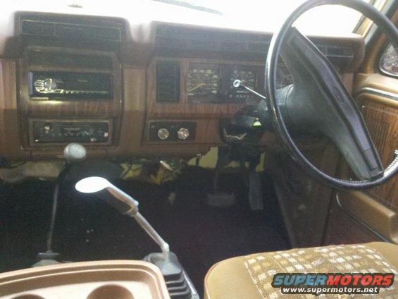 Dashboard of a truck with aftermarket radio, gauges, and dual-stick shifters. Woodgrain trim is visible