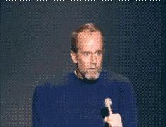 Comedian George Carlin speaking into a microphone on stage