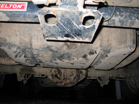 Underside view of a vehicle showing the differential, fuel tank, and a tow hitch with a 'PELTON' sticker