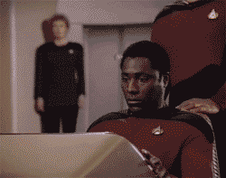 Man in Starfleet uniform looking at a computer console